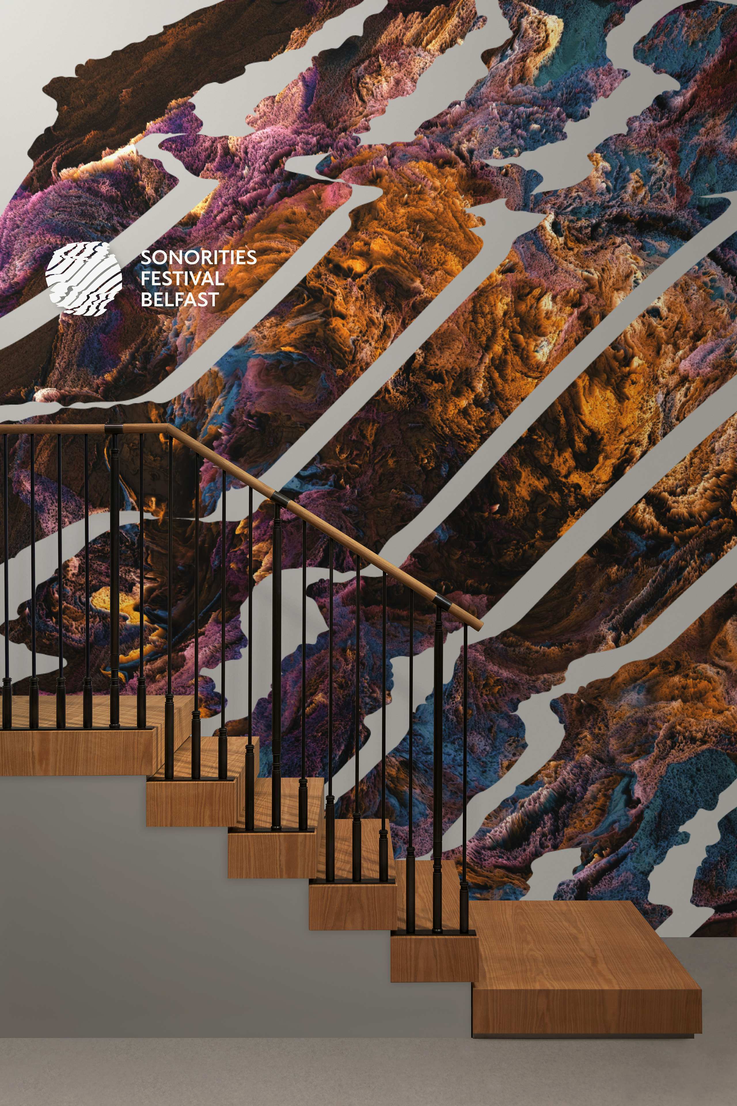 In interior stairwell with a large abstract pattern and the Sonorities Festival Belfast logo printed on the wall behind.