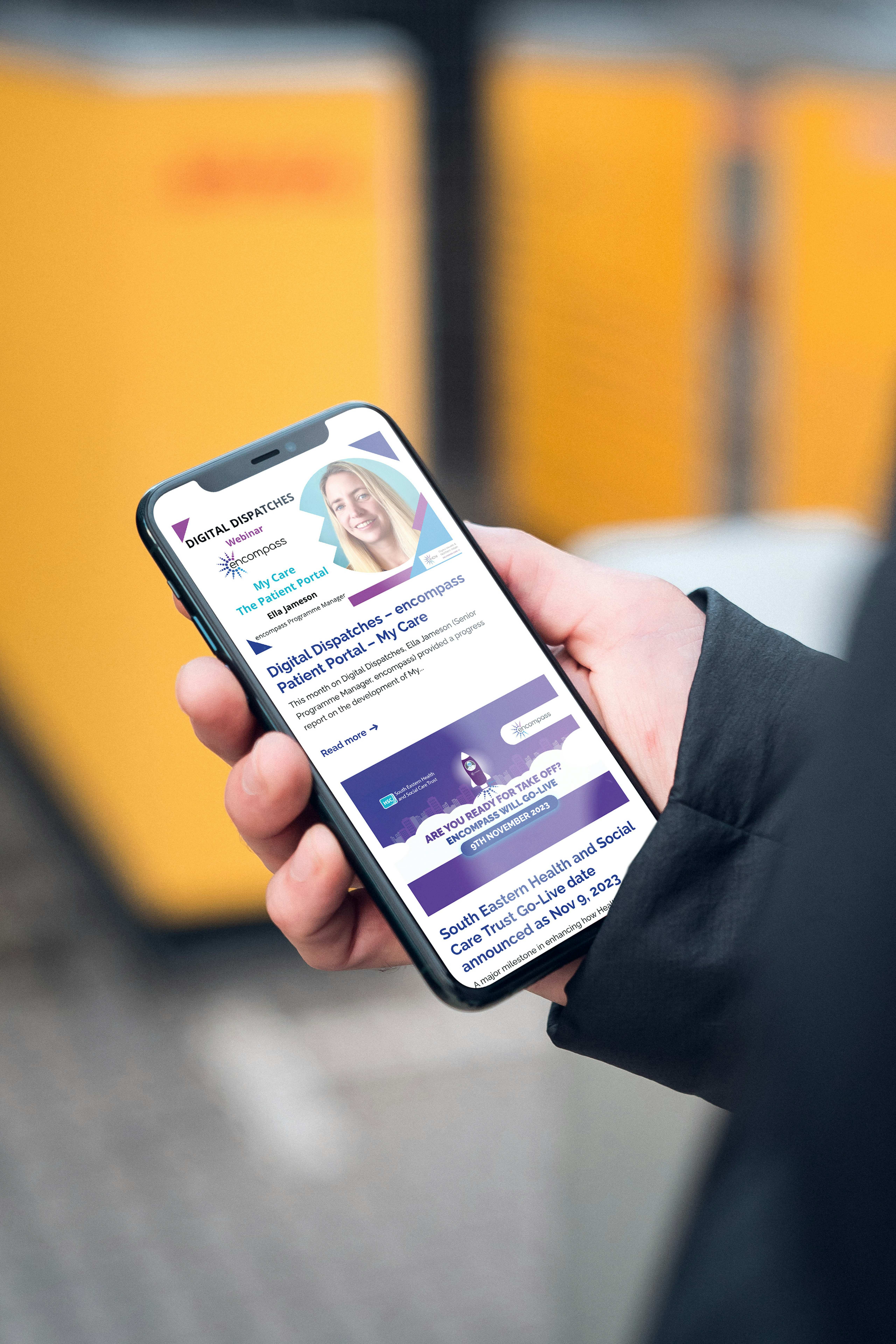 Close up of a person's hand holding and iPhone, looking at the DHCNI website.